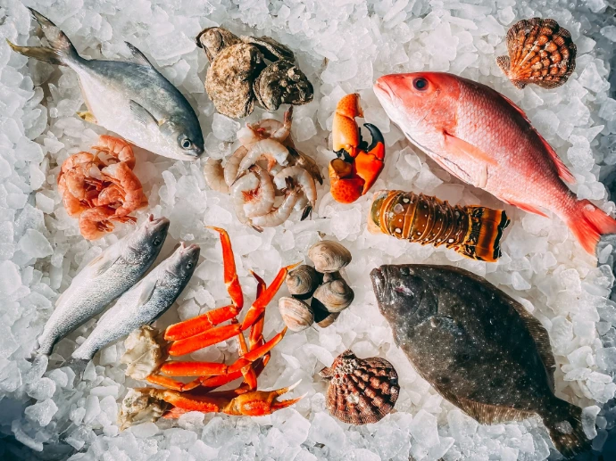 Assorted fresh seafood including fish, crab legs, shrimp, and shellfish on crushed ice